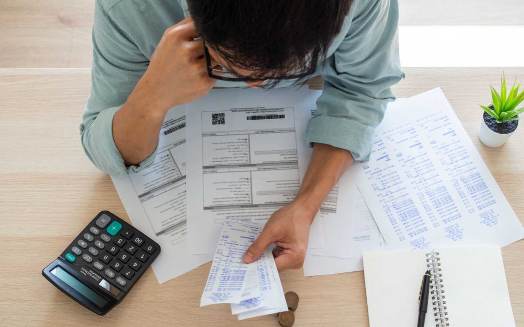 An above look at a person sitting at a desk looking at their financial statements considering whether to pay off debt or invest