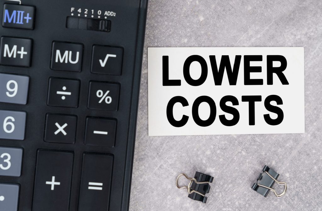 A calculator placed next to a piece of paper with text that says lower costs in capital letters.