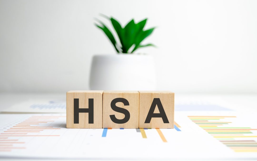 Blocks spelling out HSA sitting on a desk in front of a plant.