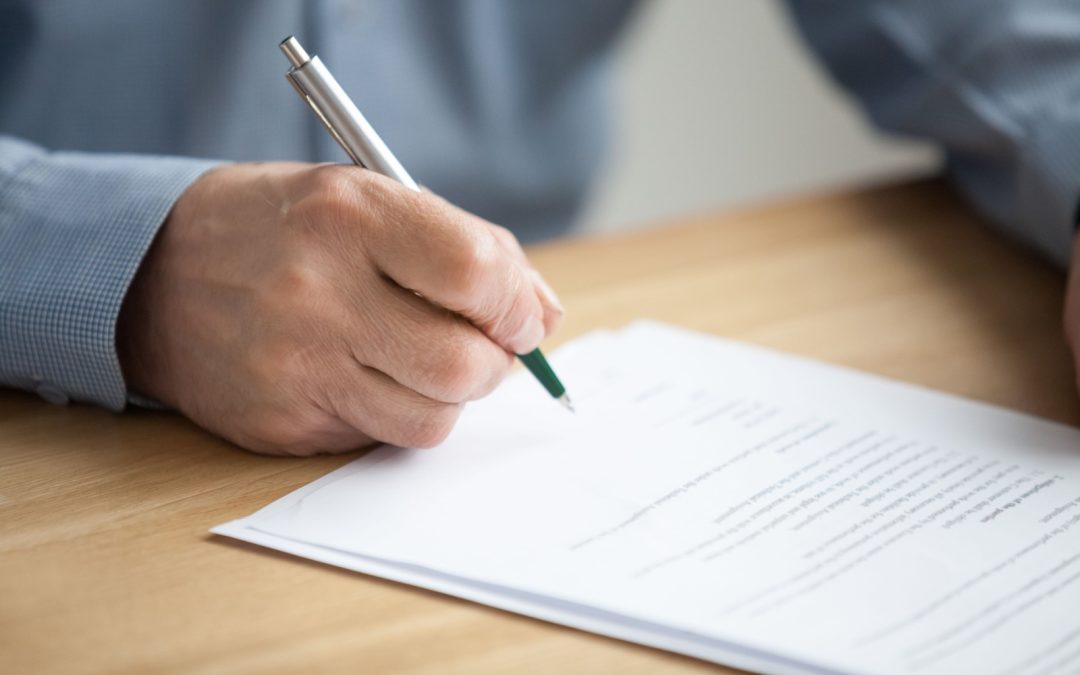 A close-up image of a hand signing paperwork for a defined benefit pension plan.