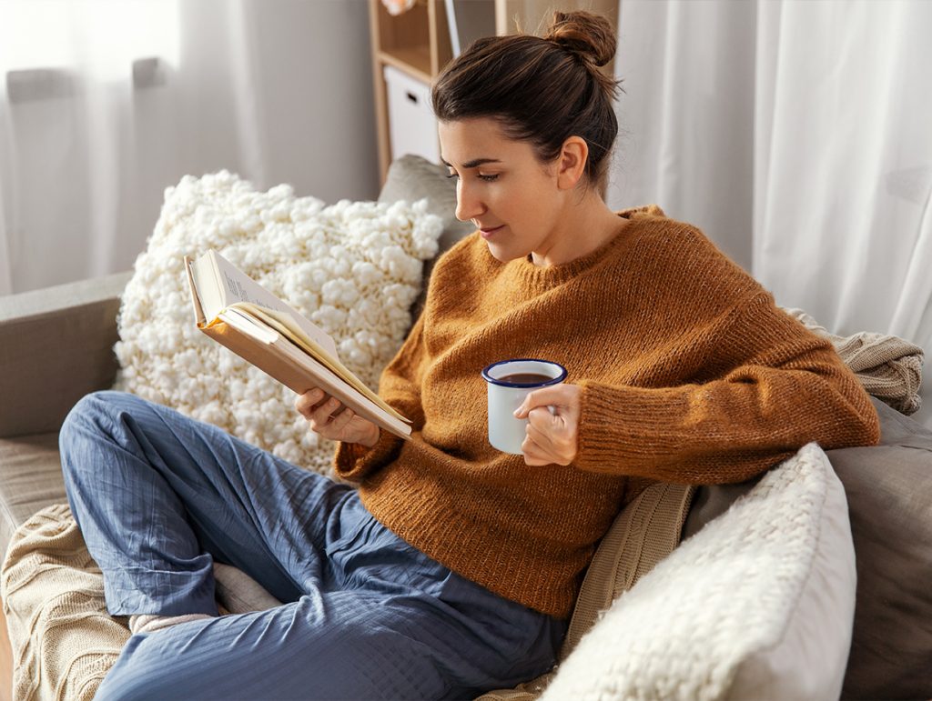 A young professional woman reading while drinking coffee