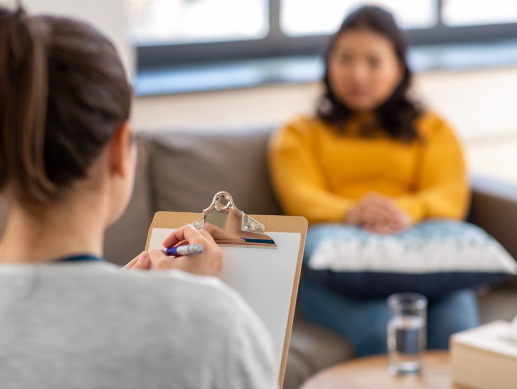 Therapist writing notes while chatting with a patient