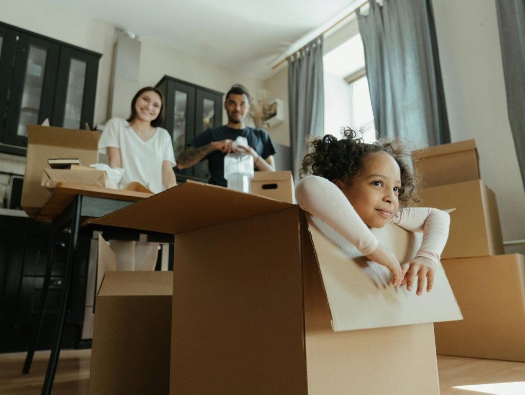 kid playing around in moving boxes in a new home