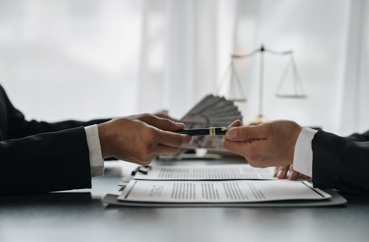 Businesswoman, investor handing money and pen to bribe lawyer, legal advisor signing investment contract dishonest fraud in financial business The concept of bribery and corruption. lawyer passing a pen to transfer wealth to the next generation