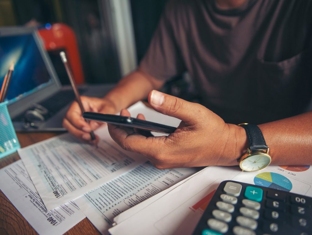 man looking through his budget, using a calculator to crunch numbers