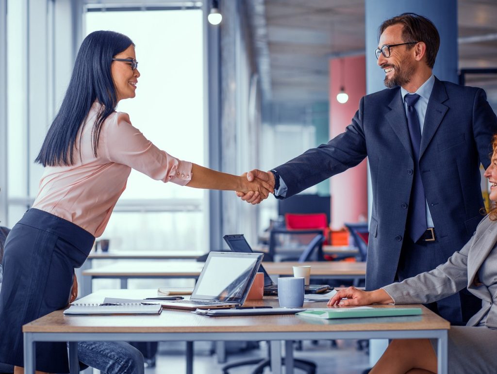 two coworkers shaking hands over a table
