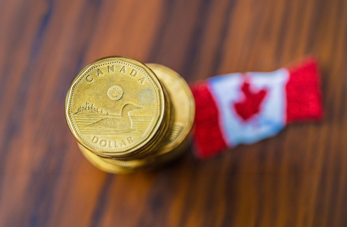 Canadian loonie beside a small canadian flag